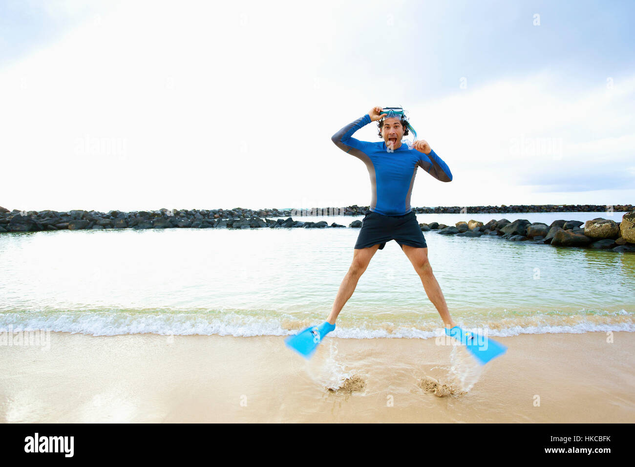 A man in snorkel gear stands at the water's edge on Lydgate Beach and