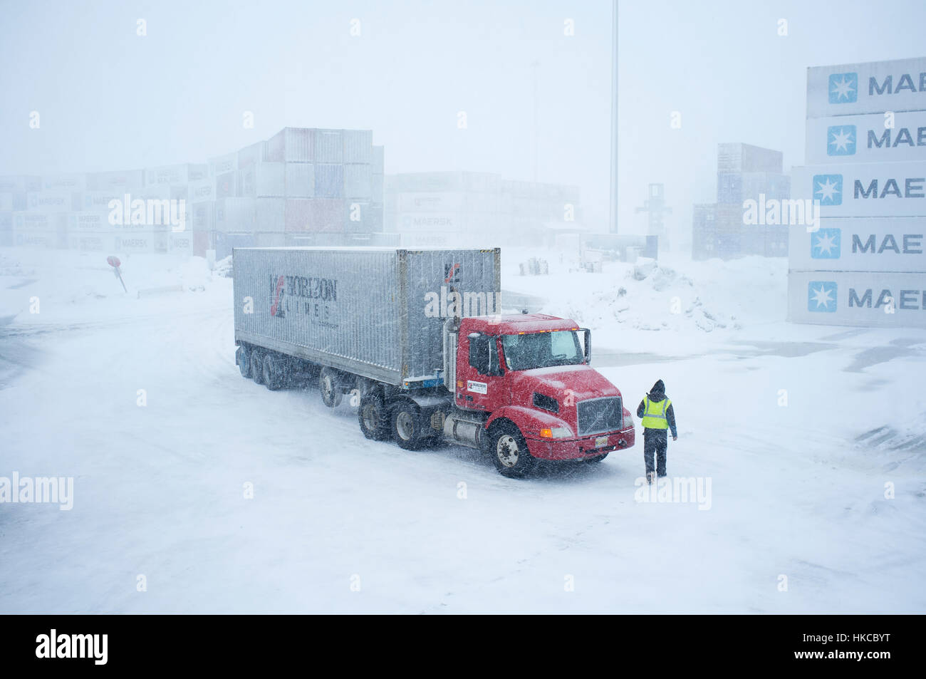 A driver walks to his Horizon Lines truck in the container yard during a snowstorm, Unalaska, Southwest Alaska, USA Stock Photo