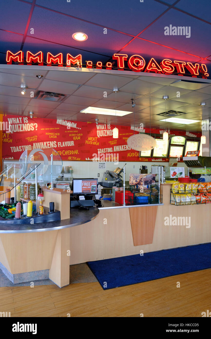 Quiznos Sub fast food chain store franchise interior, counter with no customers and no attendants, and a lit neon sign in St Thomas, Ontario, Canada. Stock Photo