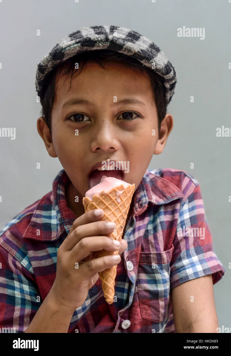 Boy with shirt and flat cap eating ice cream, portrait, Phnom Penh Province, Cambodia Stock Photo