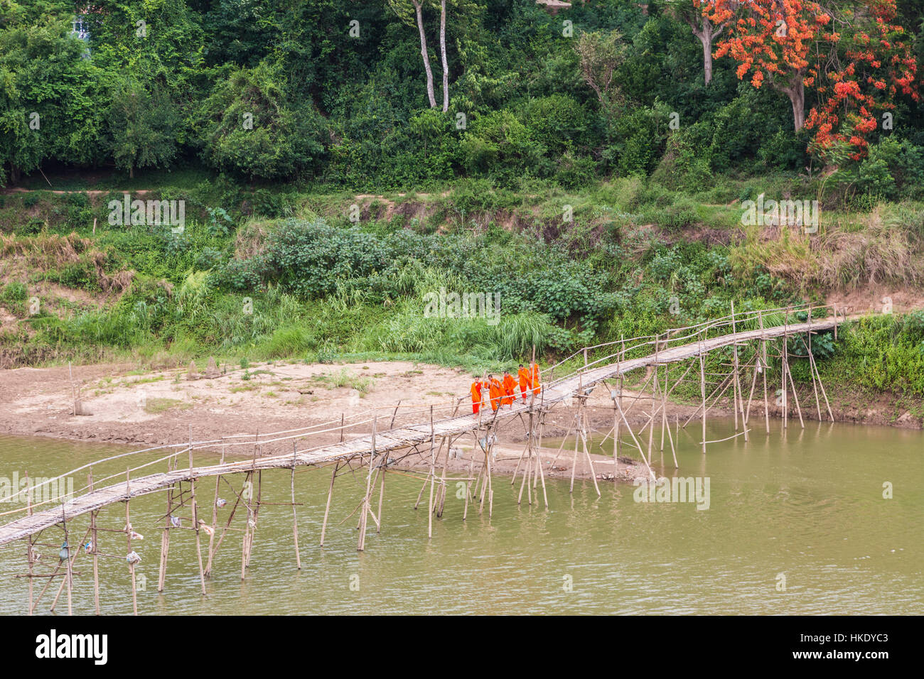 LUANG PRABANG, LAOS - MAY 16 2015: Buddhist monks cross a wooden bridge on the Nam Ou river in Luang Prabang in north Laos Stock Photo