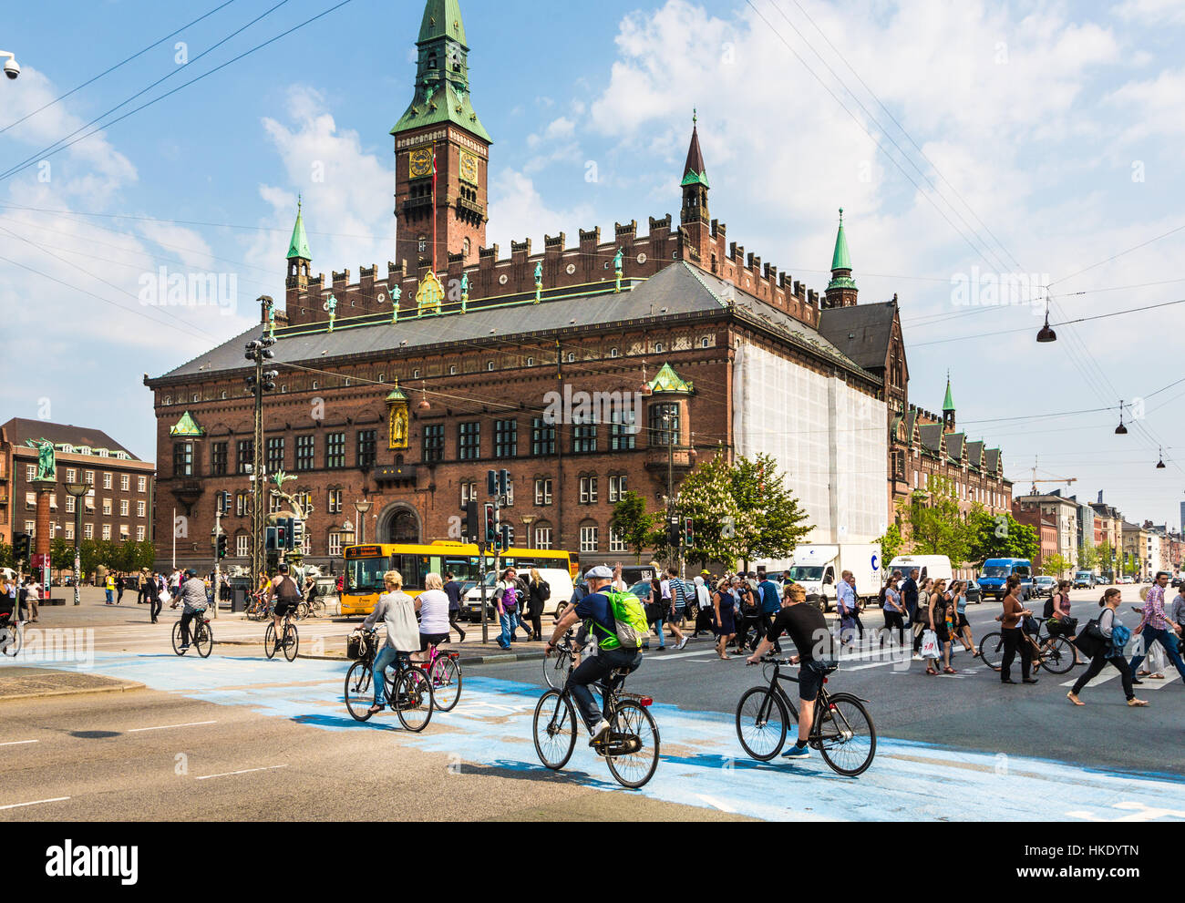 COPENHAGEN, DENMARK - MAY 24, 2016: Cyclists cross the street on a dedicated line in front of the city hall in Denmark capital city on a sunny summer  Stock Photo