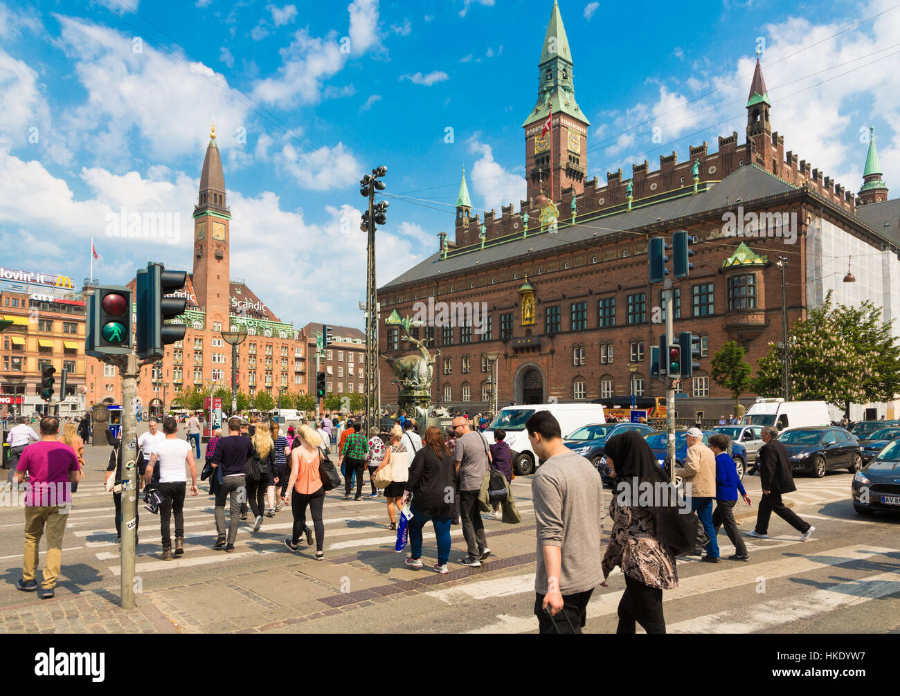 COPENHAGEN, DENMARK - MAY 24, 2016: Pedestrians cross the street in front of the city hall in Denmark capital city on a sunny summer day. Stock Photo