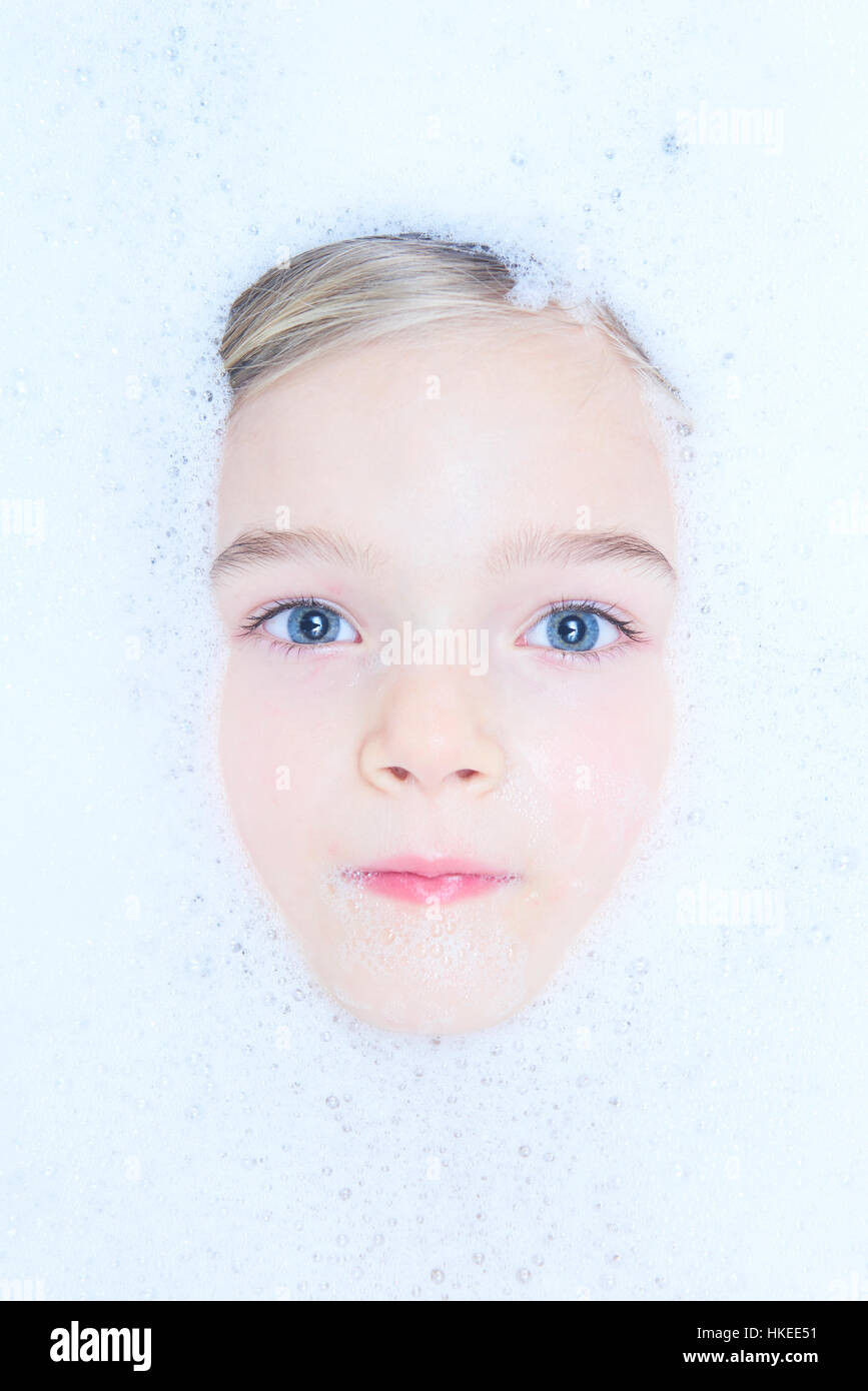 Funny little child blond girl in a bubble bath filled with soap foam Stock Photo