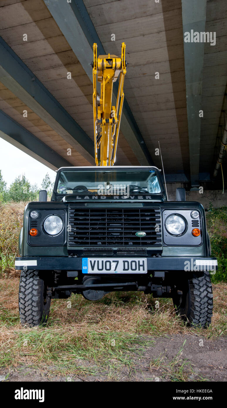 Working Land Rover Defender fitted with a high access lift cherry picker Stock Photo