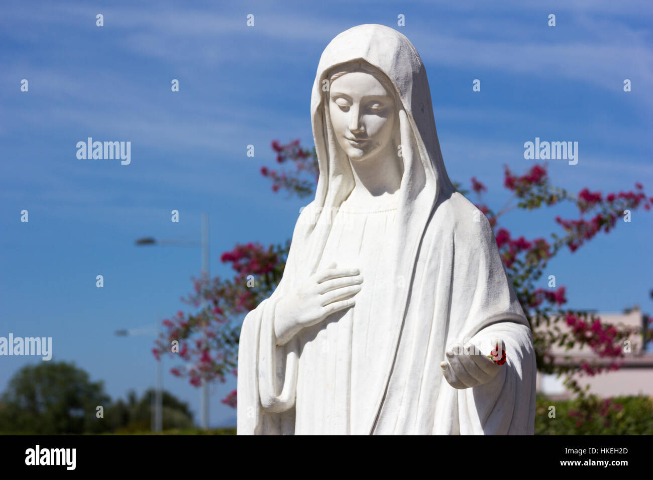 Statue of Virgin Mary in front of the church of Saint James. She is inviting her children to pray. MEDJUGORJE, BOSNIA AND HERZEGOVINA, 2016/08/20. Stock Photo