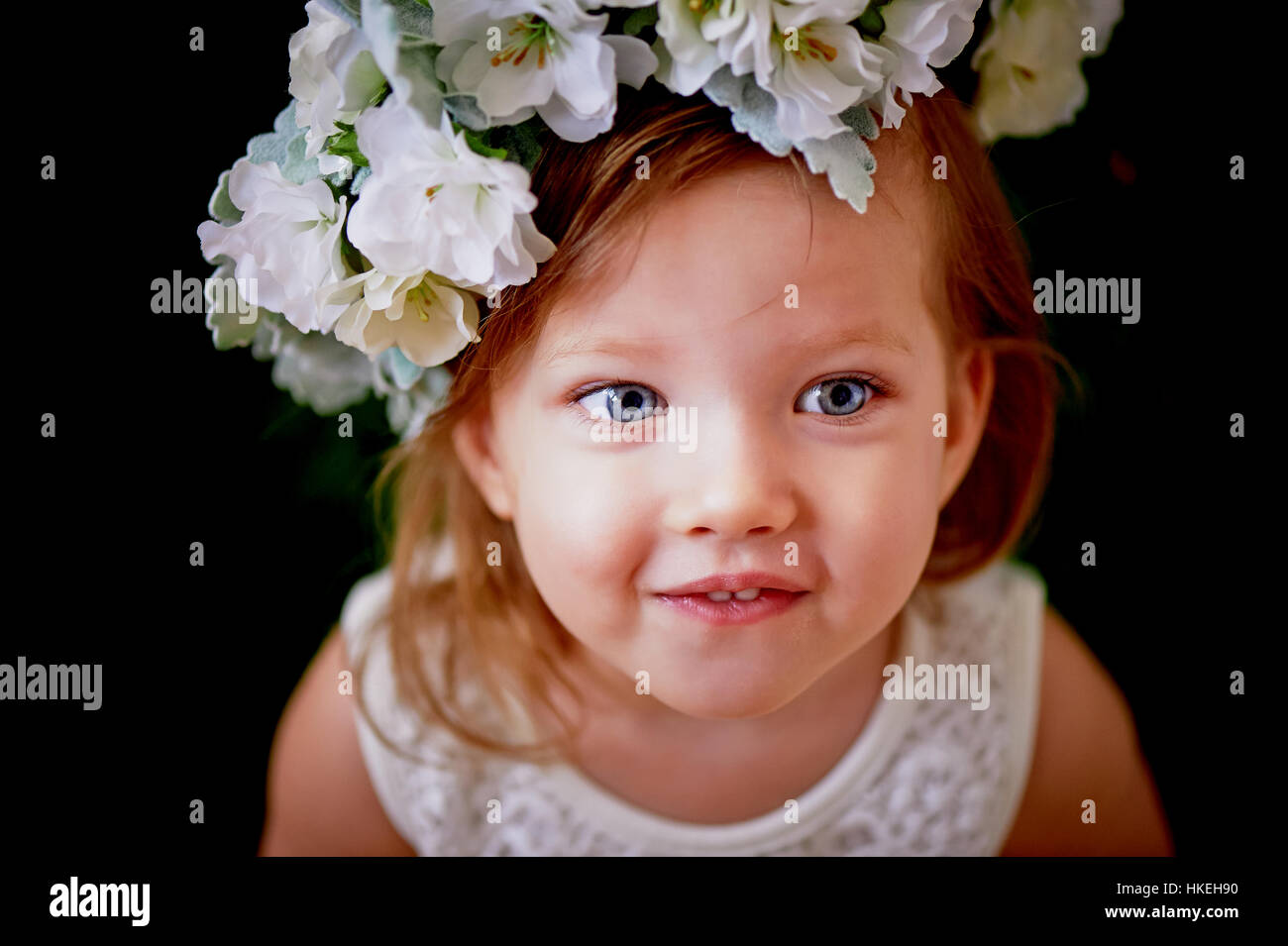 Beautiful little girl in a wreath on the head in green and white. Party ...