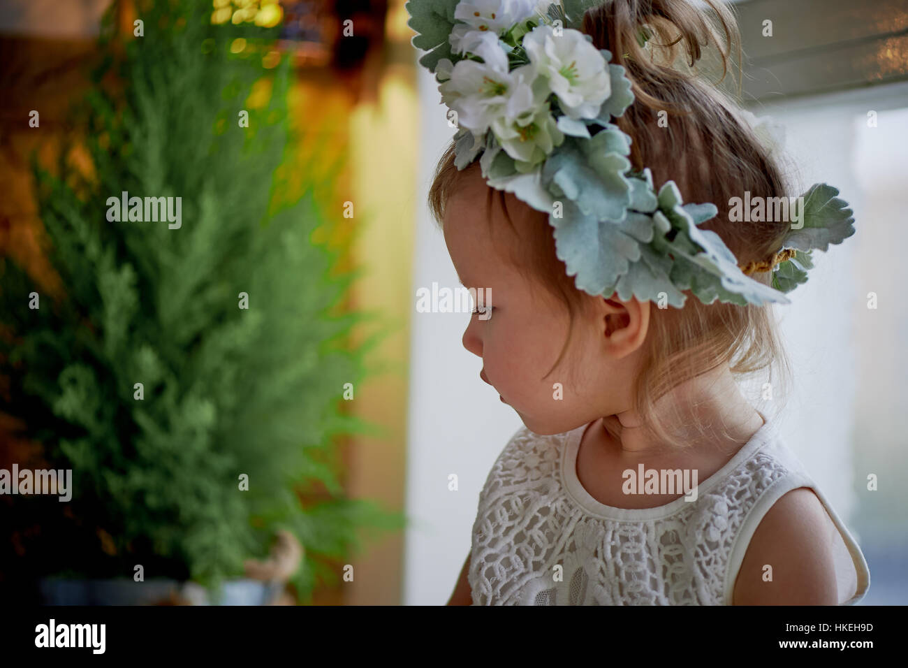 Beautiful little girl in a wreath on the head in green and white. Party ...