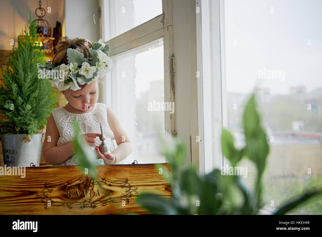 Beautiful little girl in a wreath on the head in green and white. Party ...