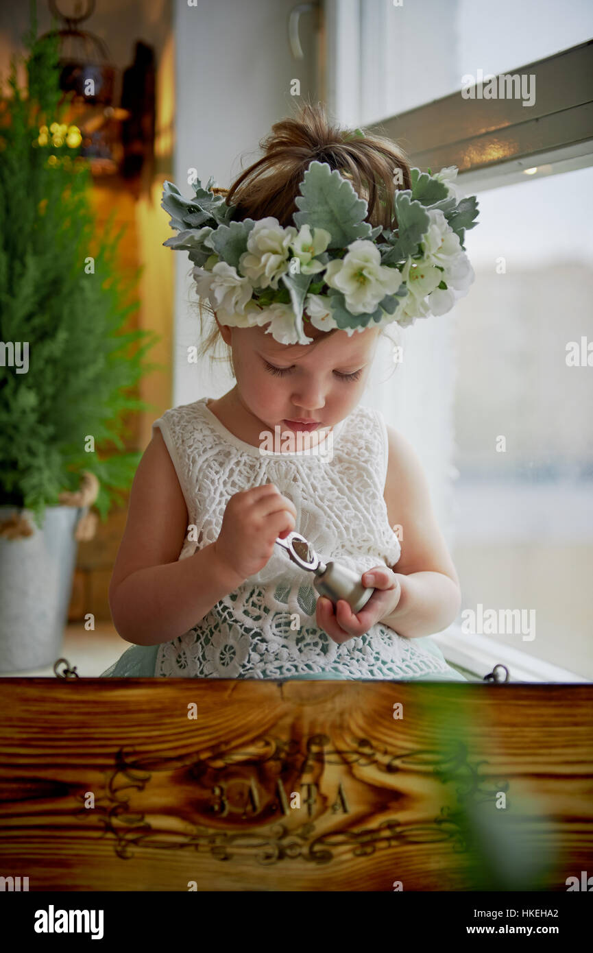 Beautiful little girl in a wreath on the head in green and white. Party ...