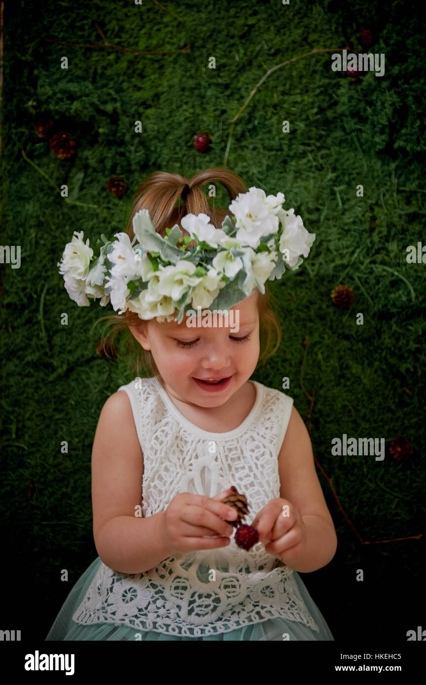 Beautiful little girl in a wreath on the head in green and white. Party ...