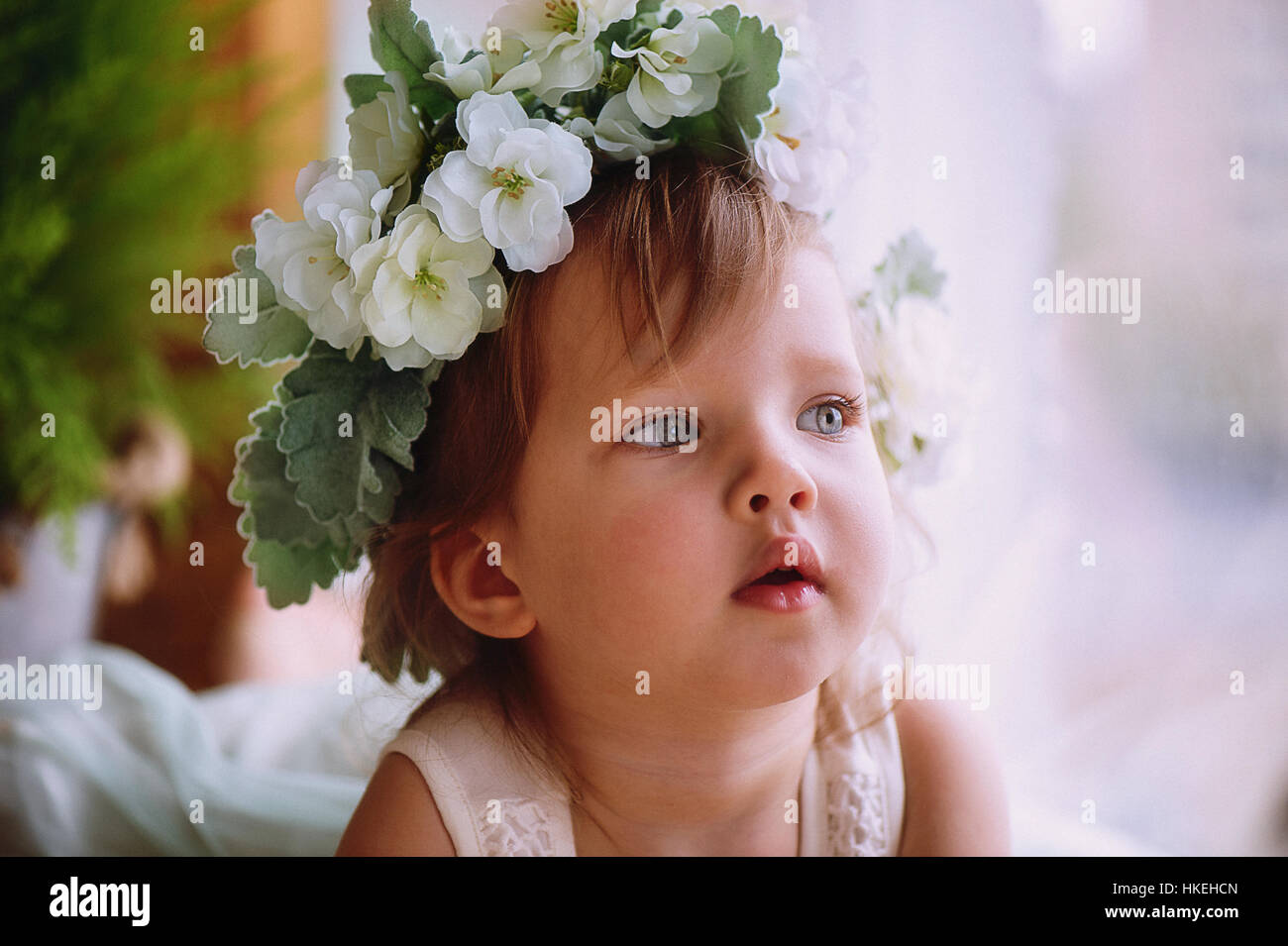 Beautiful little girl in a wreath on the head in green and white. Party ...