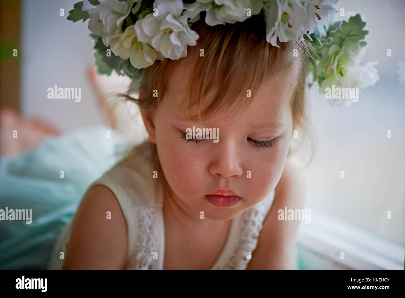 Beautiful little girl in a wreath on the head in green and white. Party ...