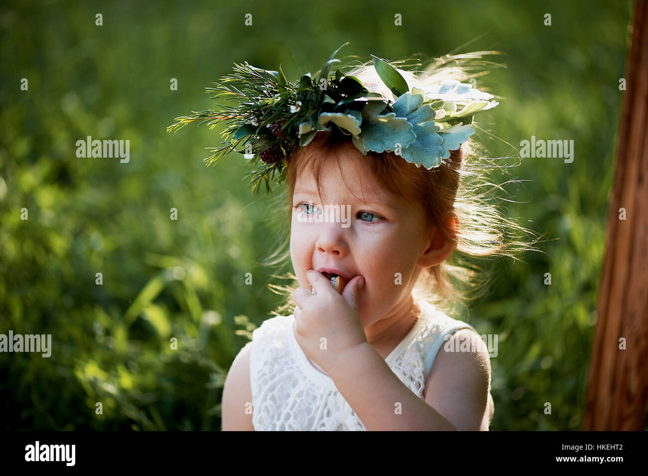 Beautiful little girl in a wreath on the head in green and white. Dress ...