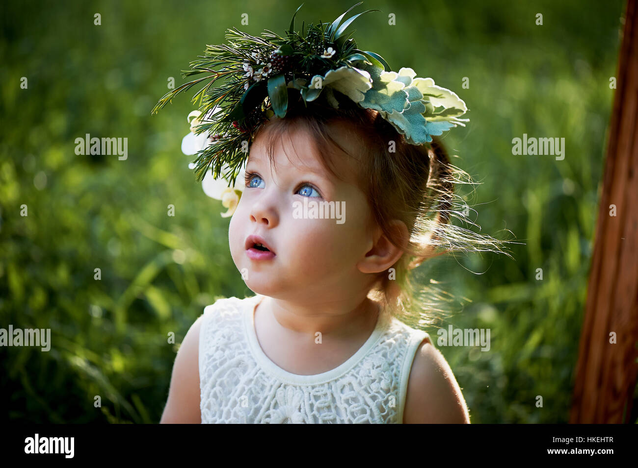 Beautiful little girl in a wreath on the head in green and white. Dress ...