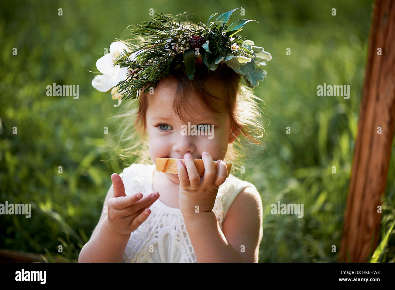 Beautiful little girl in a wreath on the head in green and white. Dress ...