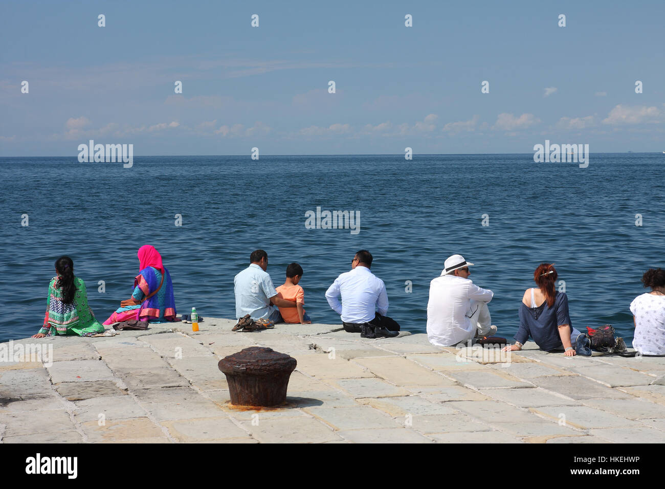 TRIESTE, ITALY - AUGUST 18, 2015: Group of turists seats on Molo Audace on August 18, 2015 in Trieste on Italy. Trieste is a popular tourist town in Stock Photo