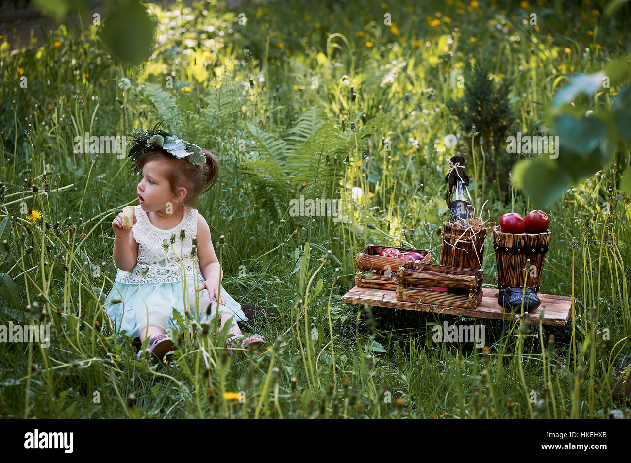 Beautiful little girl in a wreath on the head in green and white. Dress ...