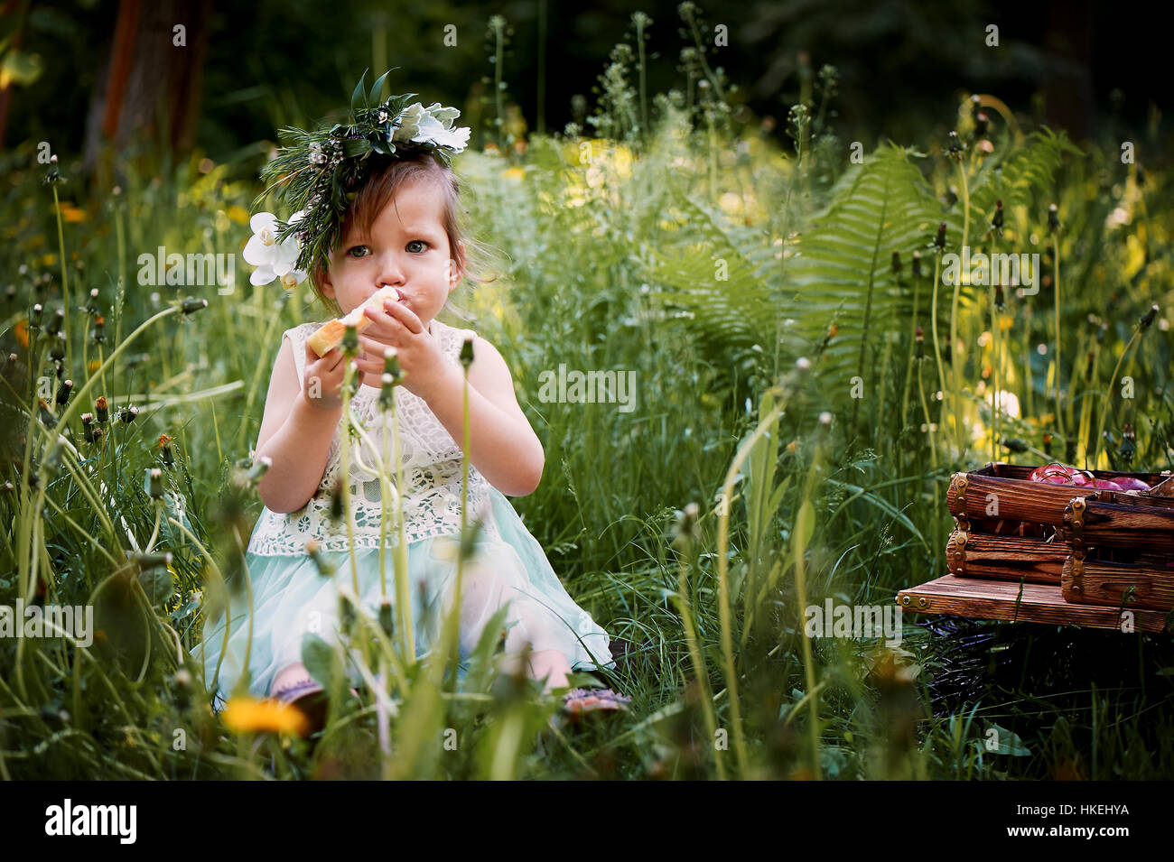 Beautiful little girl in a wreath on the head in green and white. Dress ...