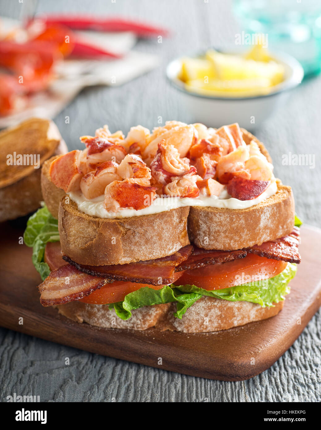 A delicious lobster club sandwich with bacon, lettuce, tomato, and mayonnaise on toasted bread. Stock Photo