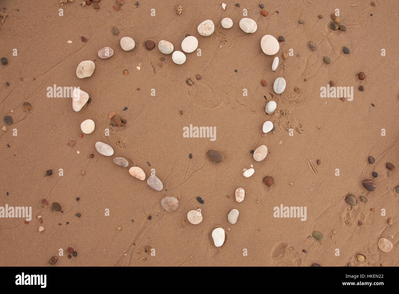 Heart from stones, Pebbles arranged in heart shape on sand Stock Photo