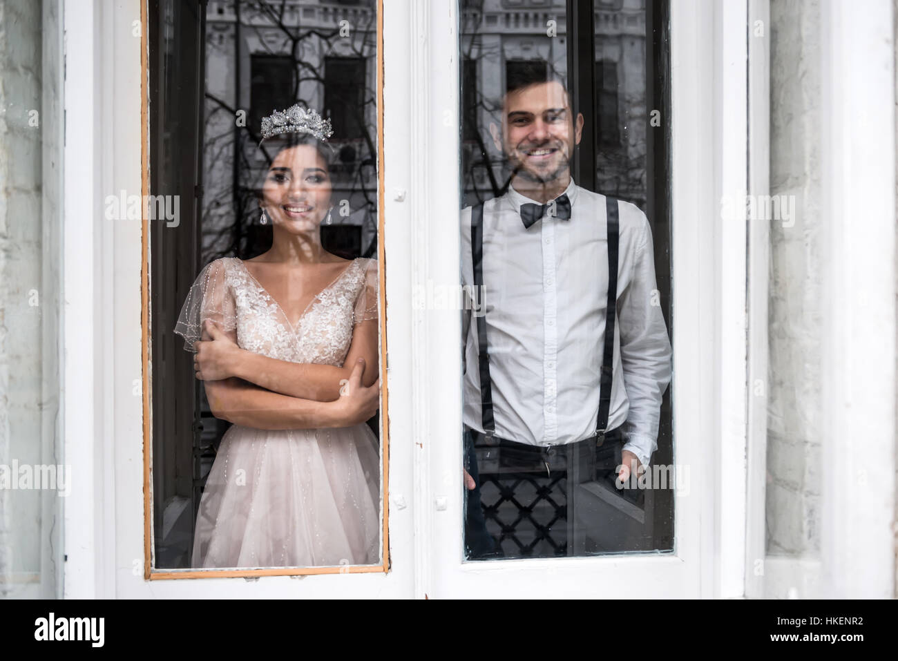 The bride and groom standing near a large window Stock Photo - Alamy