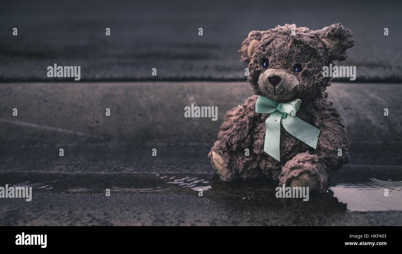 Sad wet teddy Bear left behind on kerb offset copy space Stock Photo