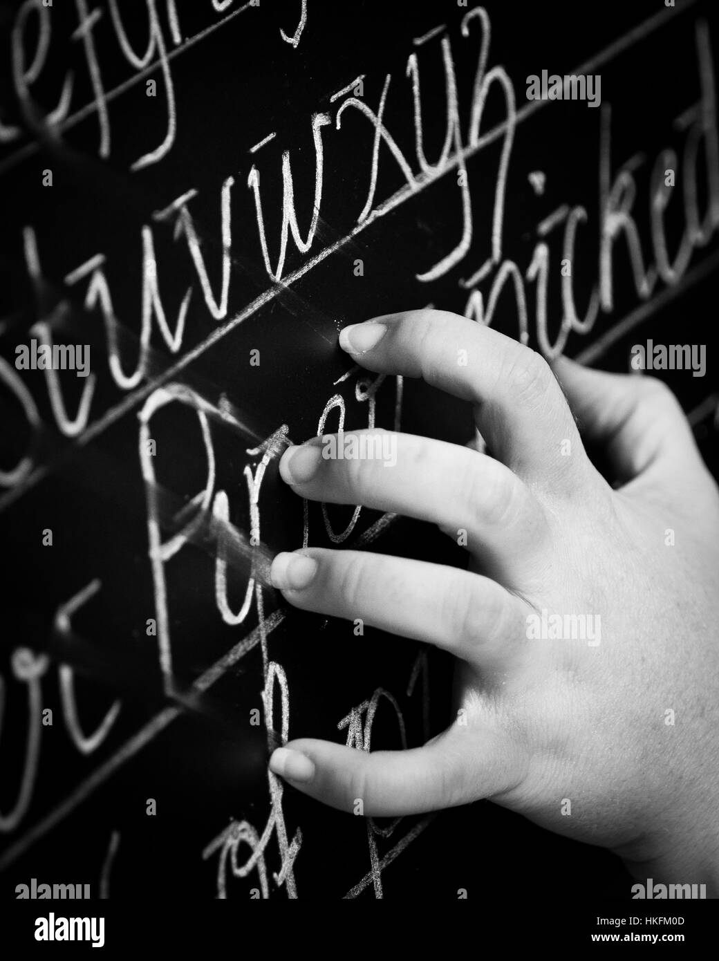 Finger nails scratching down black board with chalk writing Stock Photo