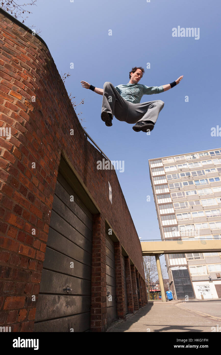 A parkour freerunning athlete jumping down from a wall onto concrete Stock  Photo - Alamy