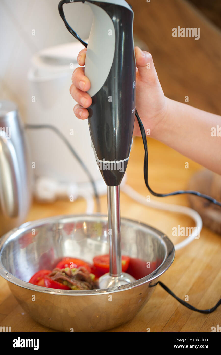 hand using manual blender to blend tomatoes. mixer, food, blender, preparation. Stock Photo