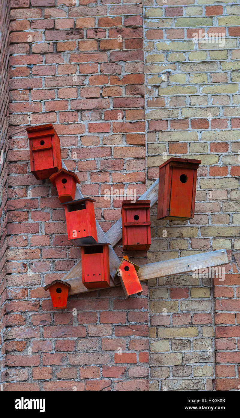 Red nesting boxes on brick wall - urban installation Stock Photo