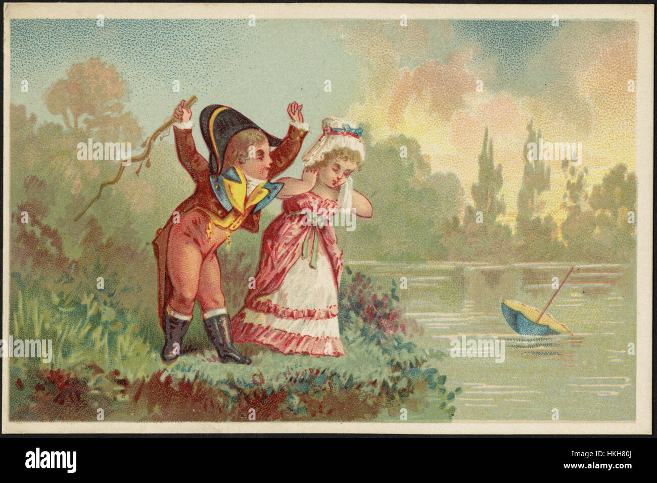 Boy and girl in historical costume at the water's edge, looking at the umbrella that has floated away. Stock Photo