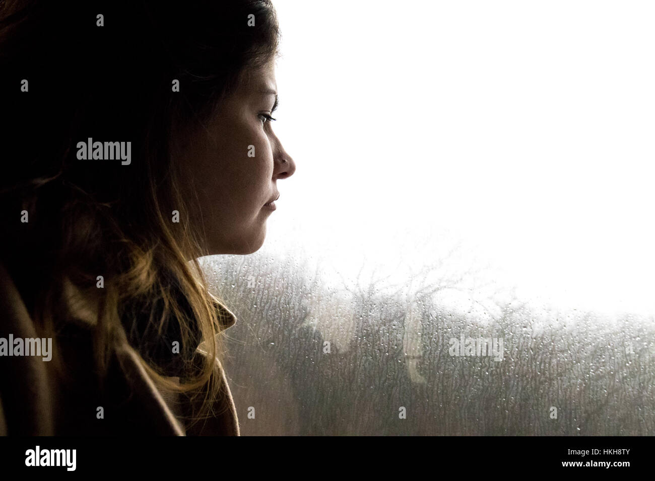 Beautifull girl looking at the bus window while is raining outside. Stock Photo
