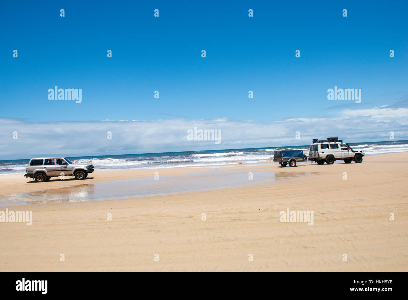 4WD cars driving down 75 Mile Beach on Fraser Island, Queensland Australia Stock Photo