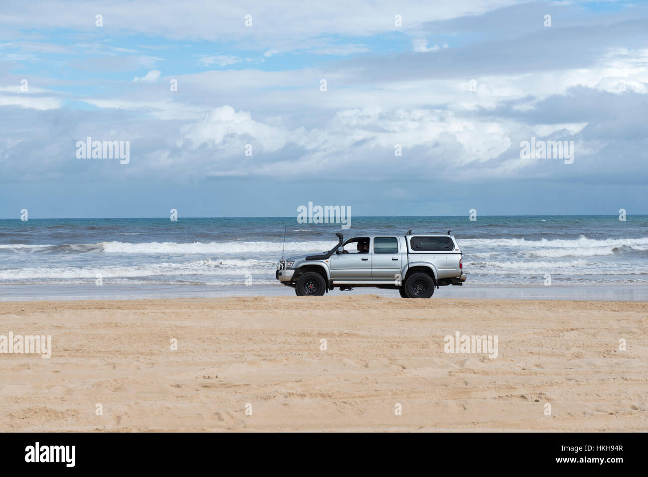 A 4WD car driving down 75 Mile Beach on Fraser Island, Queensland Australia Stock Photo