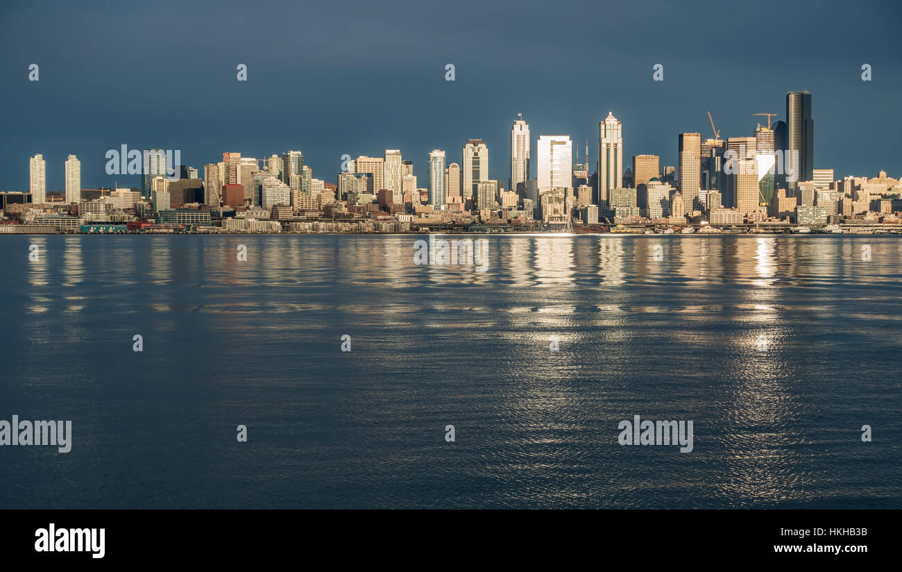 As the sun sets the buildings of the Seattle skyline are reflected in Elliott Bay. Stock Photo