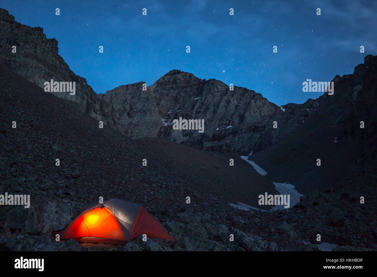 A glowing tent underneath a night sky in the Elk Mountains in Aspen, colorado Stock Photo