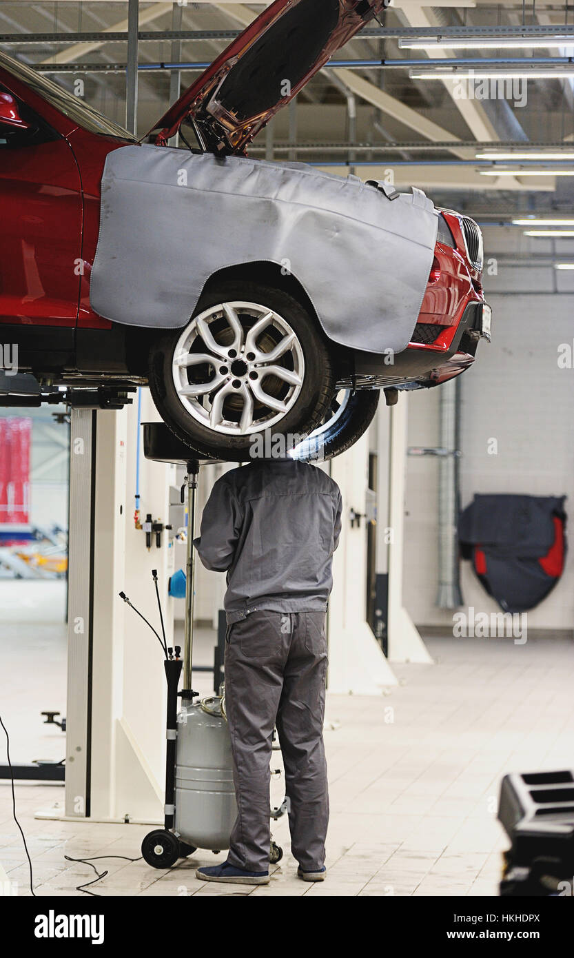 mechanic repairing suspension in car in big and clean garage Stock Photo