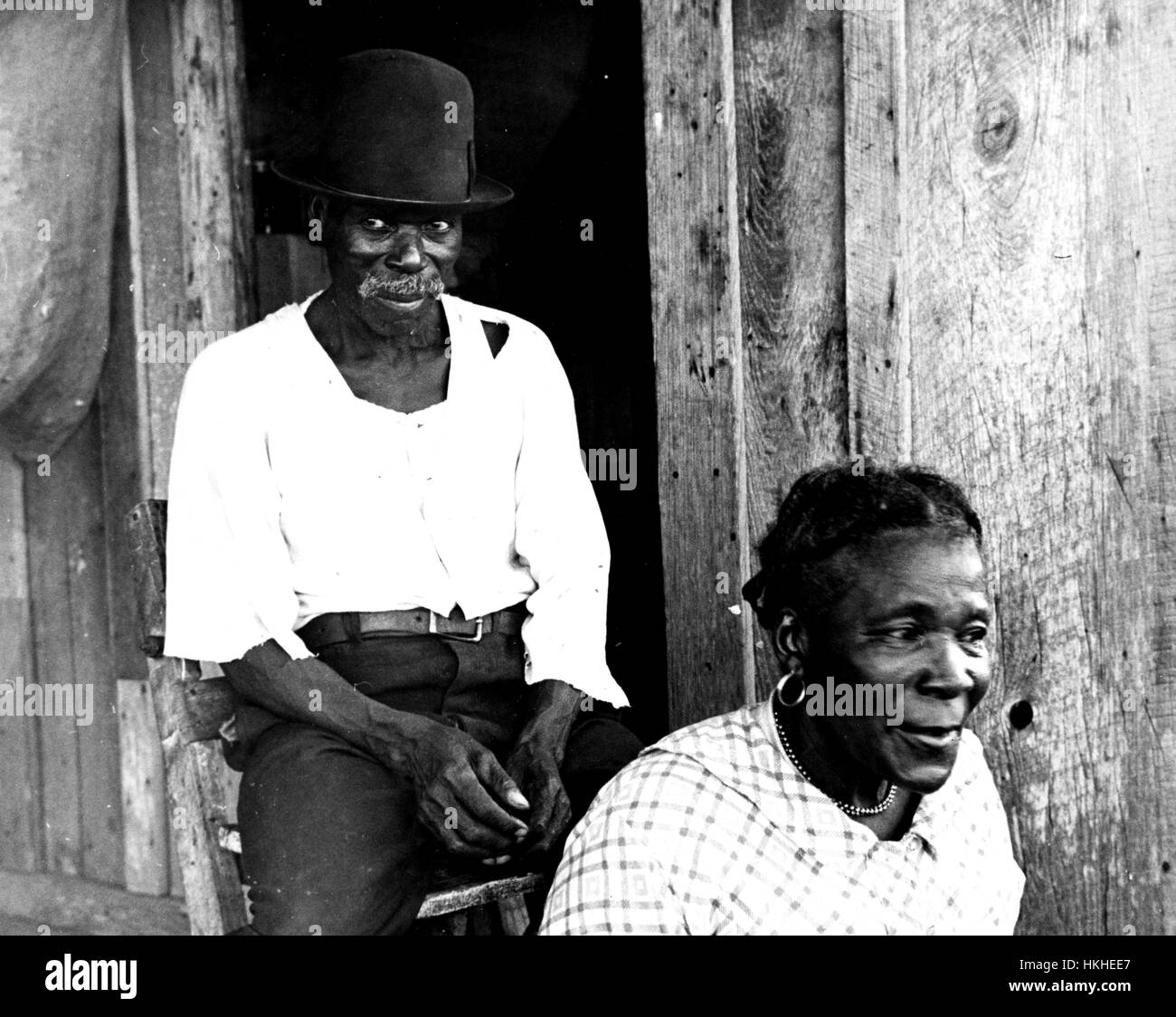 Black and white photograph of two mature African-American sharecroppers, a woman sitting in the foreground, a man sitting behind her, by Walker Evans, American photographer best known for his work for the Farm Security Administration documenting the effects of the Great Depression, Pulaski County, Arkansas, 1935. From the New York Public Library. Stock Photo