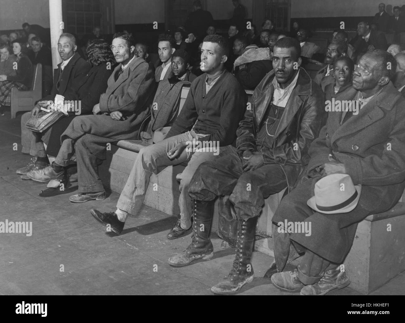 A photograph of men and women sitting on long wooden benches in a court room, most people are wearing formal clothing as they are attending a Superior Court trial in relation to an automobile accident, the crowd is a mix of witnesses and spectators, Oxford, North Carolina, November, 1939. From the New York Public Library. Stock Photo