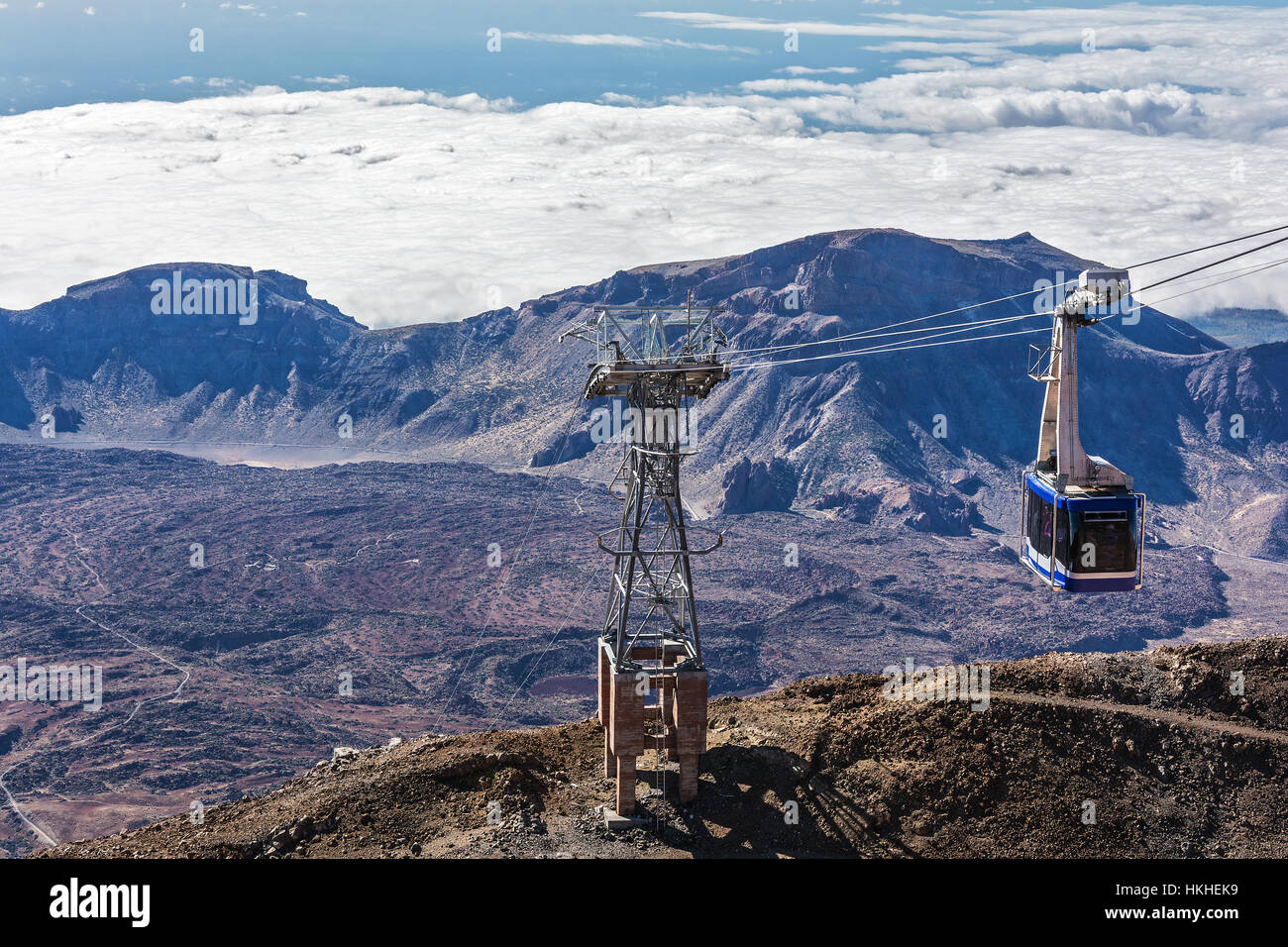 Blue cabin cable car with tourists climbing ropes stretched to the
