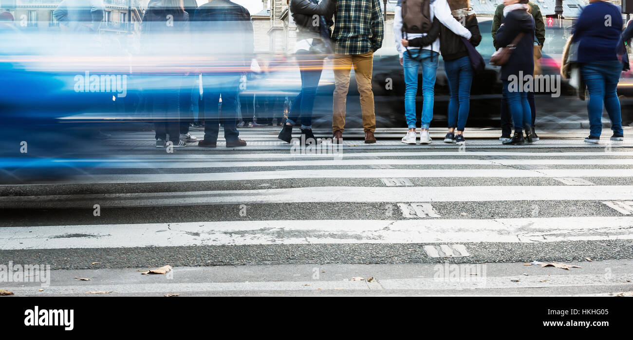 street scene with waiting people at the pedestrian crossing and blurred ...