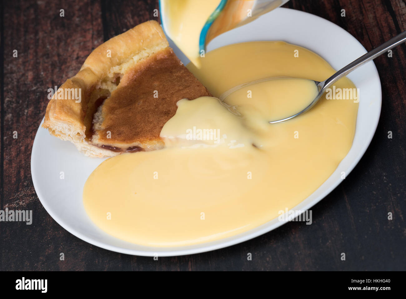 A slice of Bakewell pudding with custard. Stock Photo