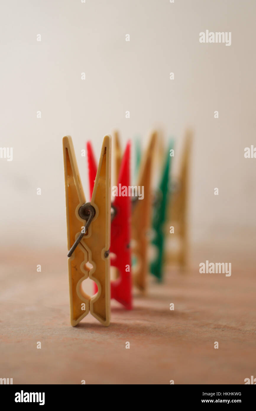 A line of five plastic pegs arranged with the front peg in focus and the others blurred Stock Photo