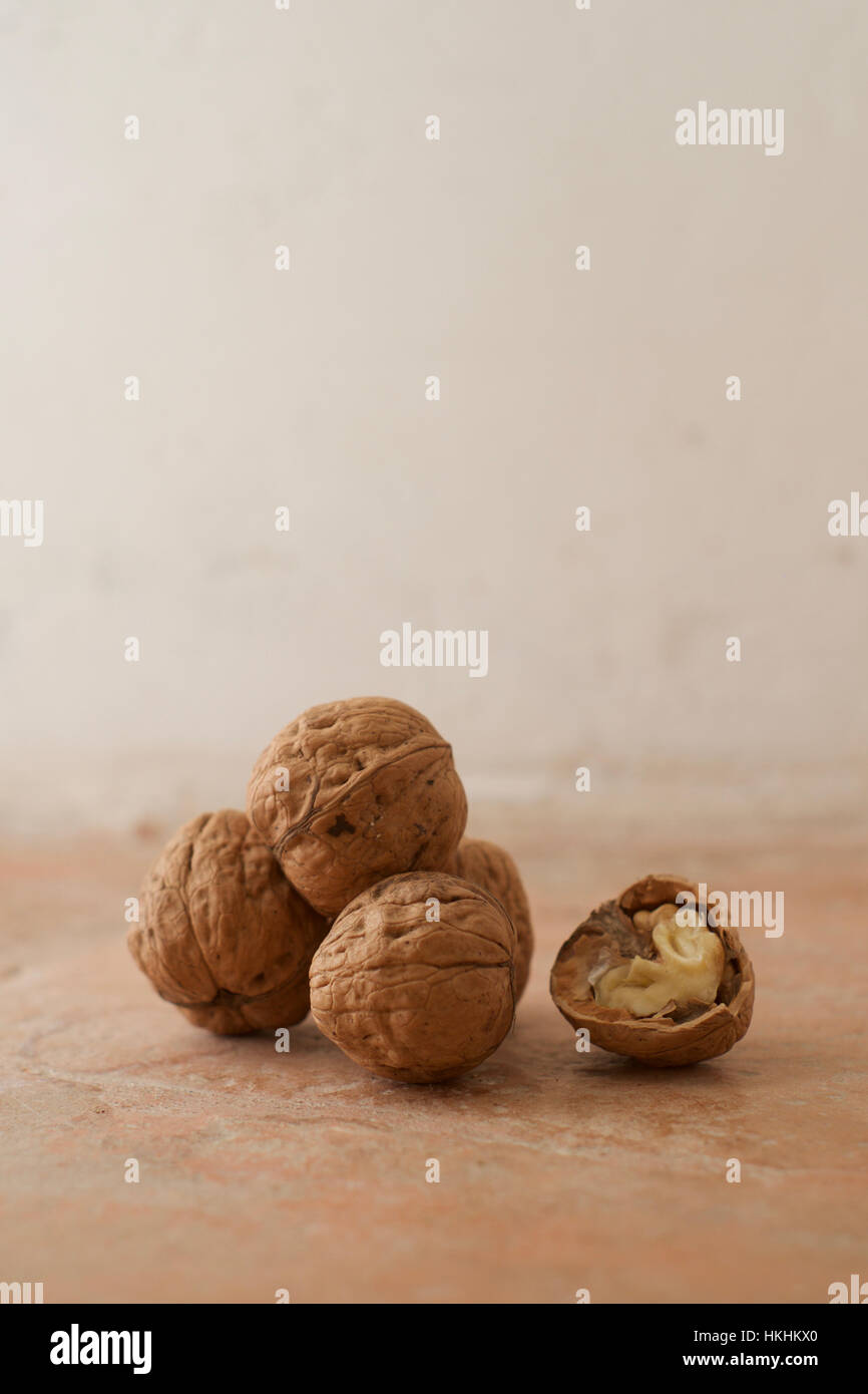 A stack of four whole walnuts with one half walnut showing the nut