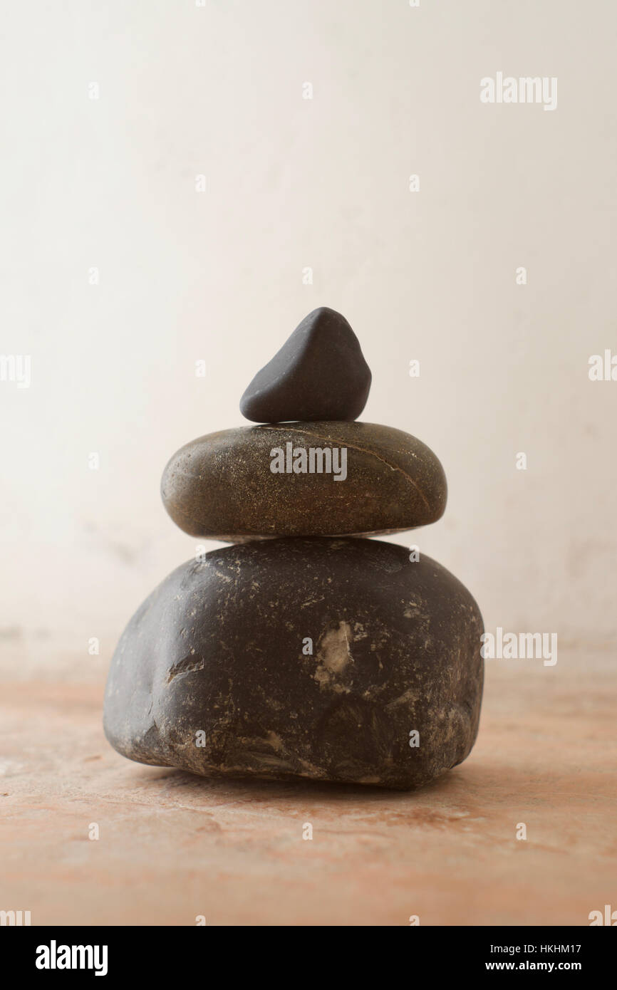 A stack of pebbles with black tones against a rustic background Stock Photo