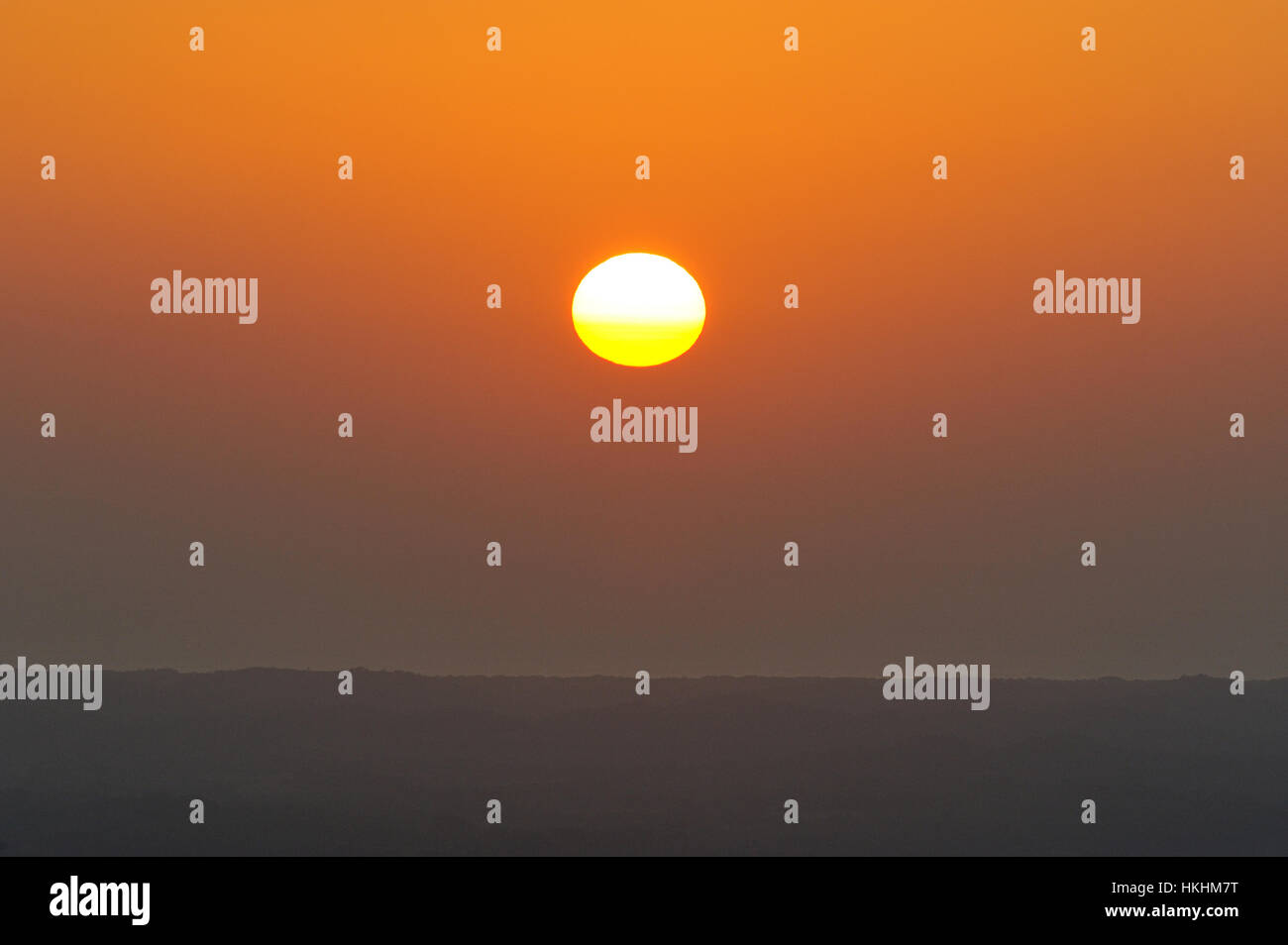 Red sun next to horizont line in orange sky Stock Photo