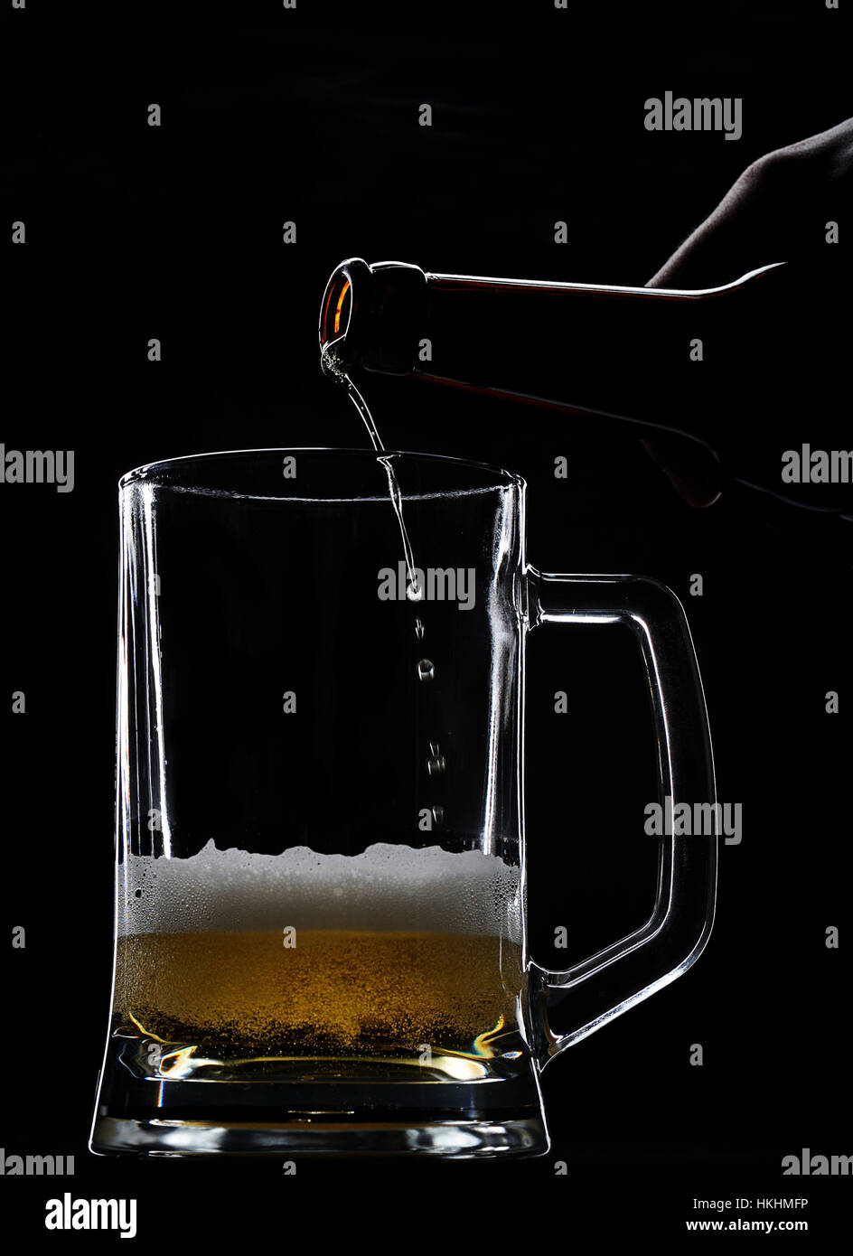 beer come from bottle in empty glass on black Stock Photo