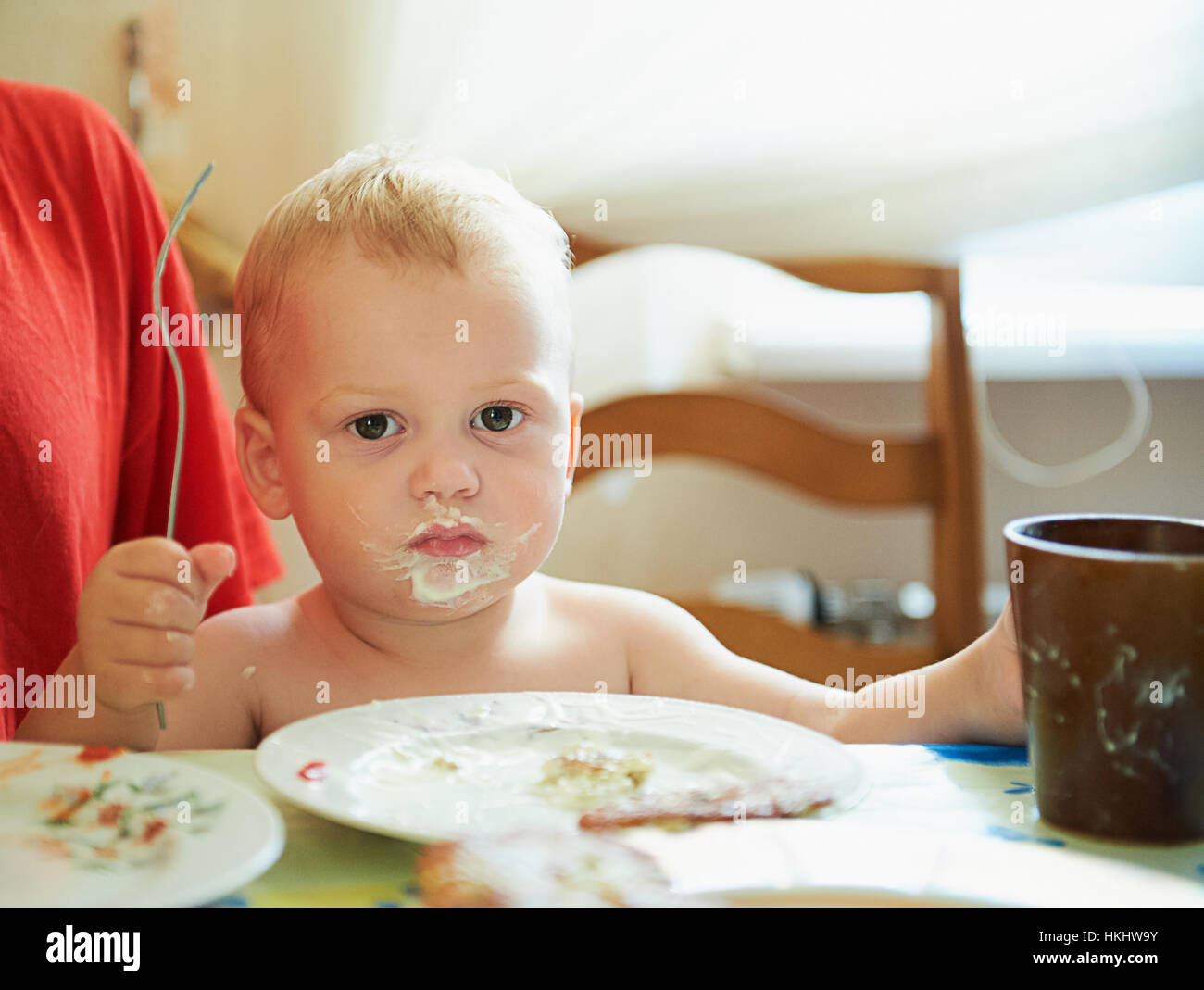 small boy eating with dirty mouth inside house Stock Photo