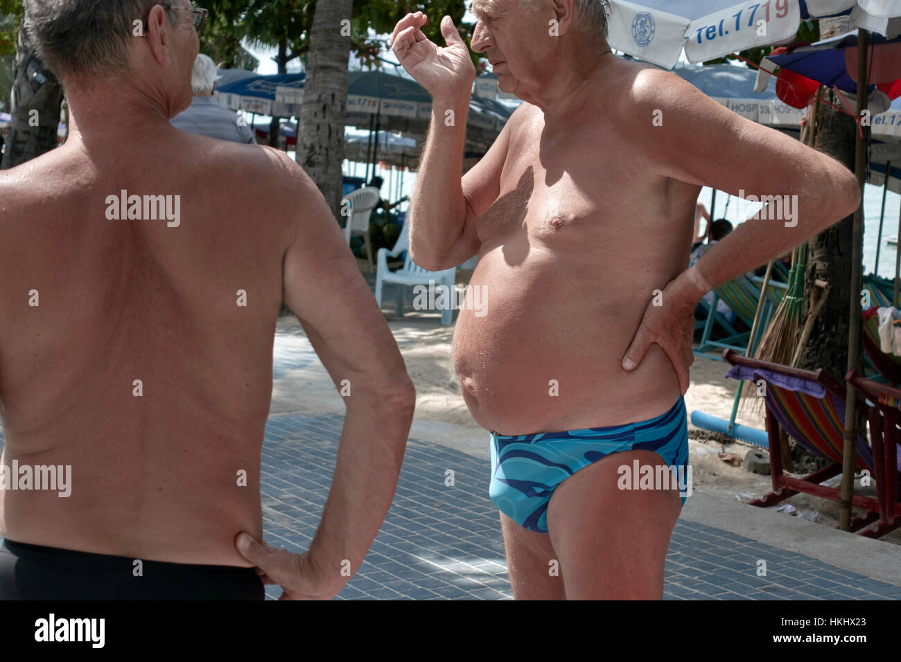 Two mature men with pronounced stomachs and wearing speedos swimming trunks  chatting on the street Stock Photo - Alamy